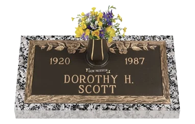 Bronze flat memorial marker on a granite base with an attached vase of flowers