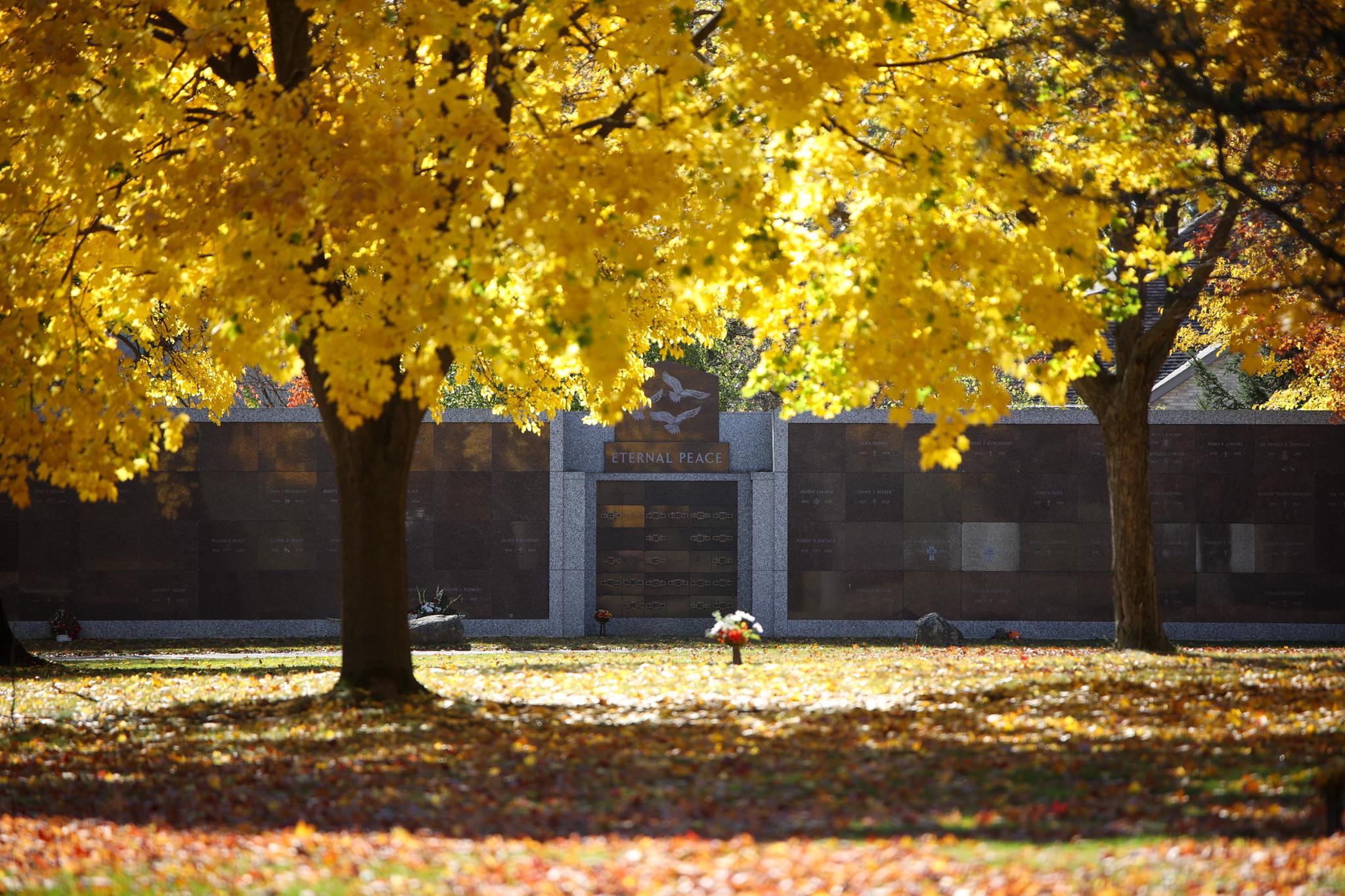 A columbarium wall labeled "Eternal Peace" surrounded by yellow autumn trees