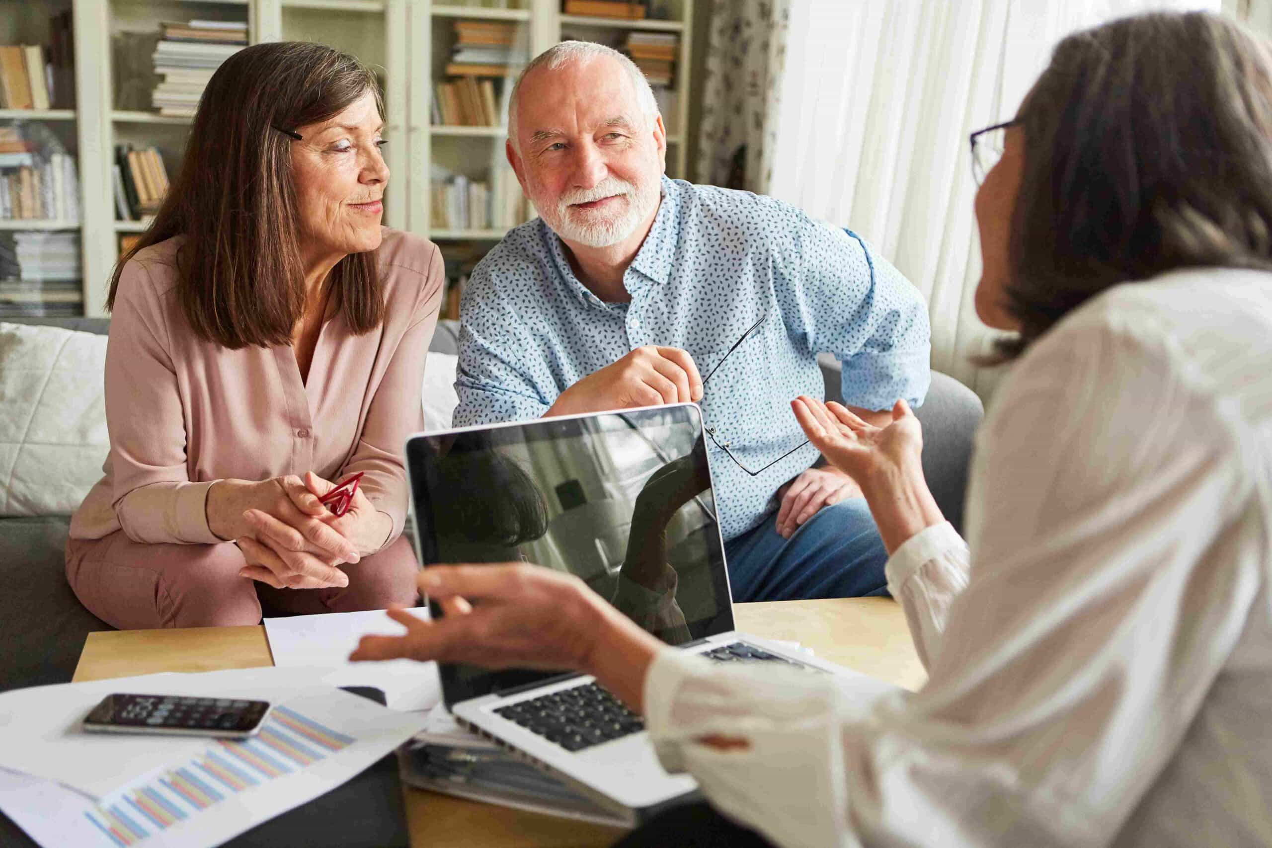 An older couple listening to a consultant during a meeting with a laptop and documents on the table
